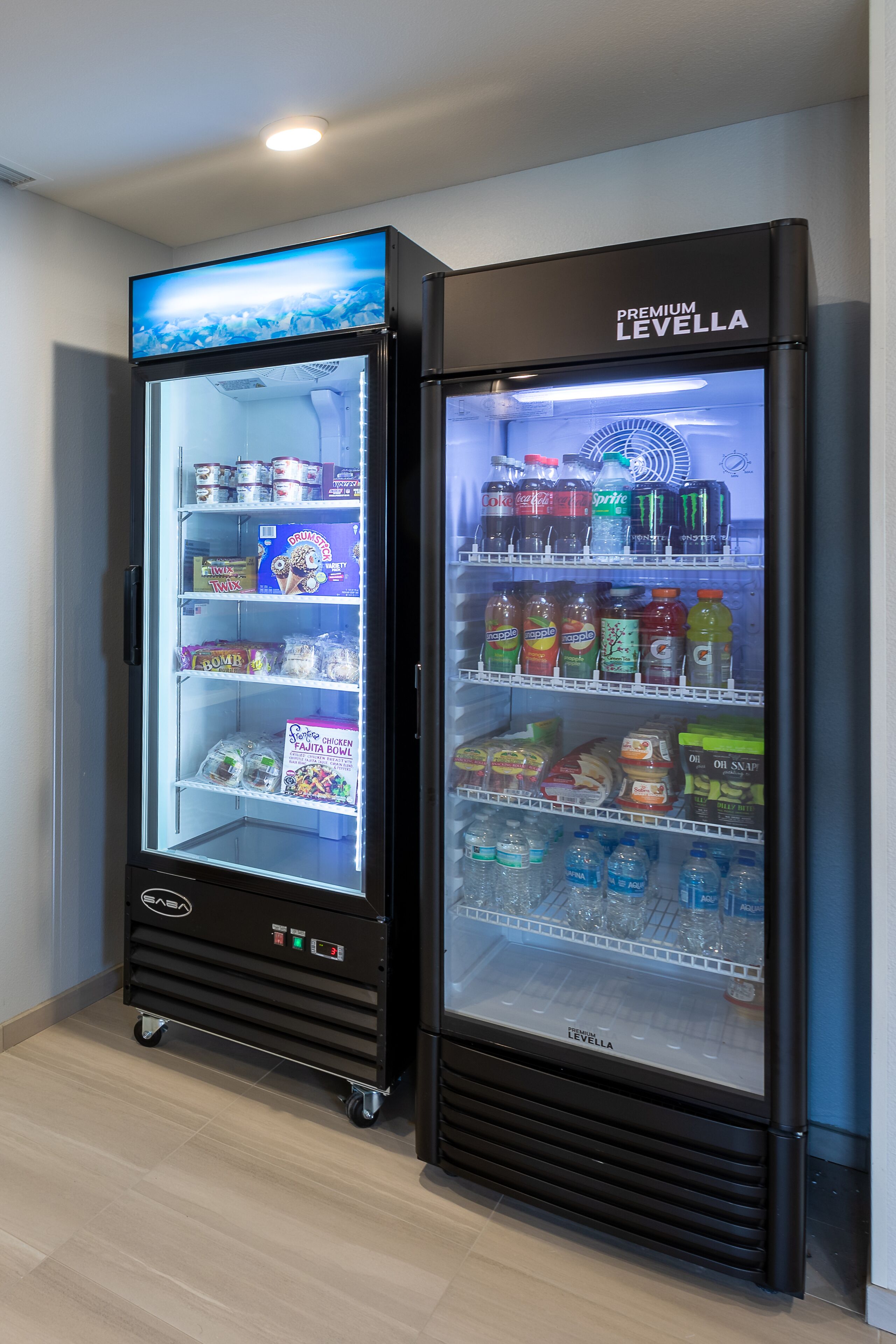 Zwei schwarze, gekühlte Getränkespender mit dem Aufdruck 'PREMIUM LEVELLA', gefüllt mit verschiedenen Getränken und Snacks.