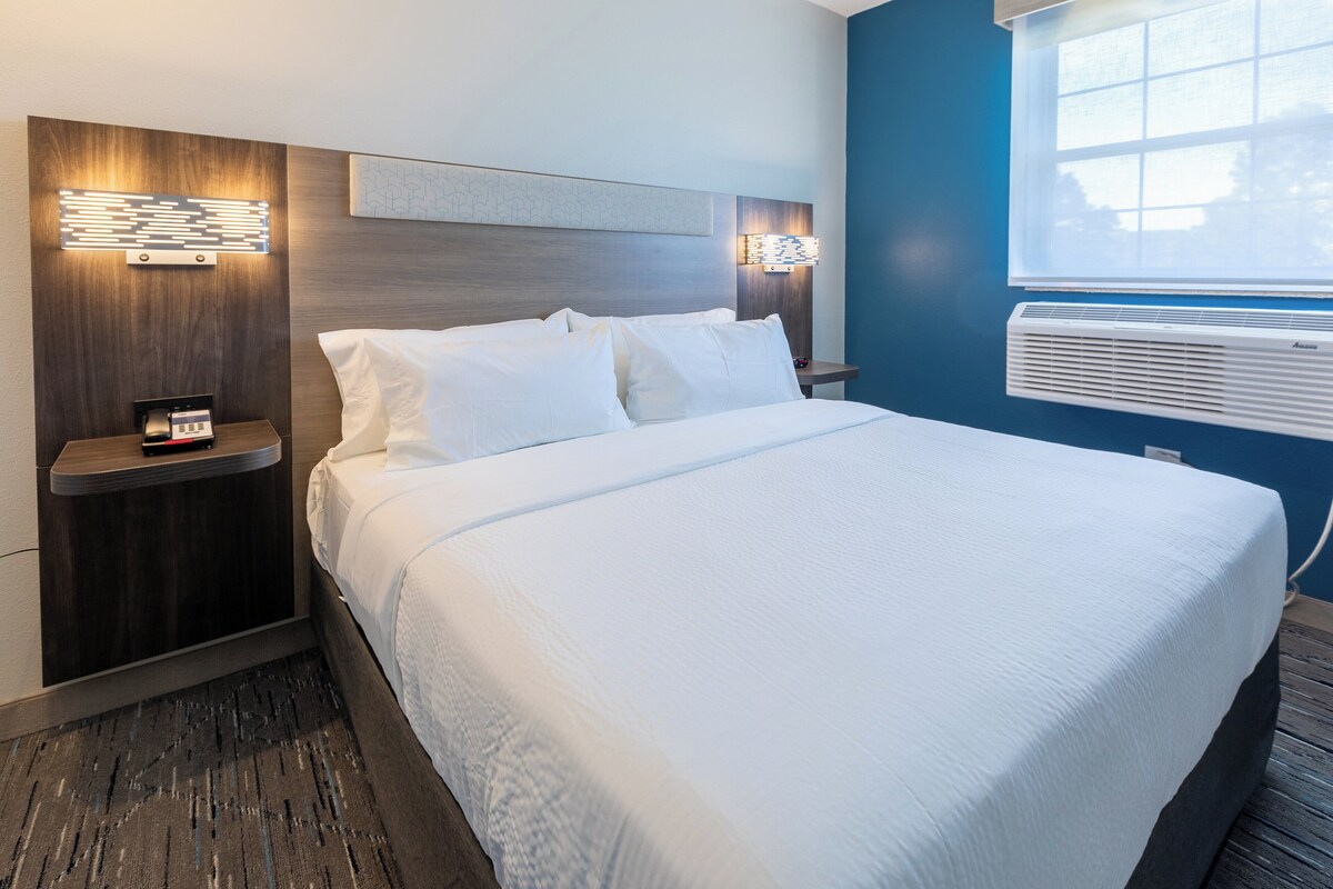 A neatly made bed with white linens, a wooden headboard, and two bedside tables with lamps.
