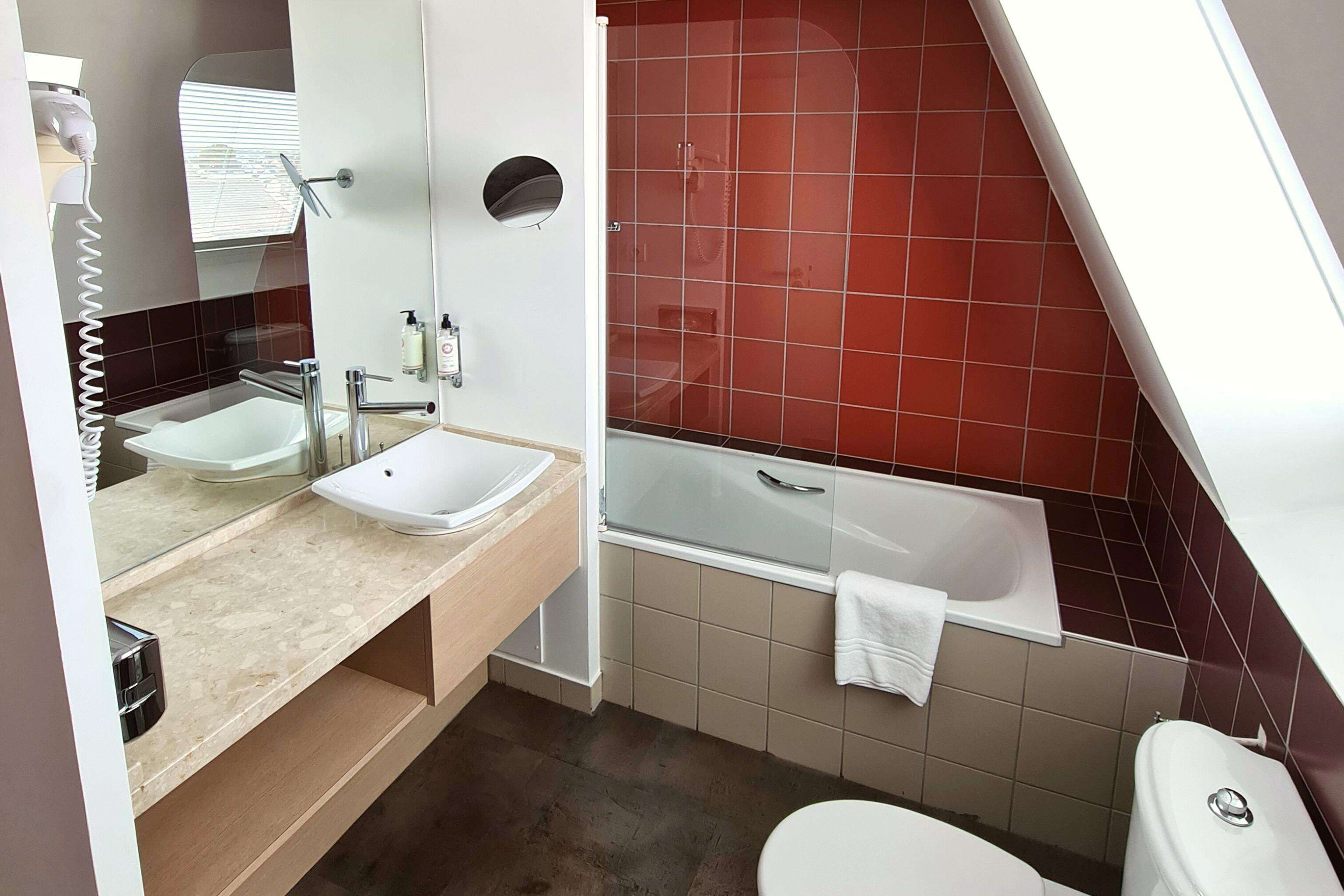 A modern bathroom with a sink, mirror, and bathtub.