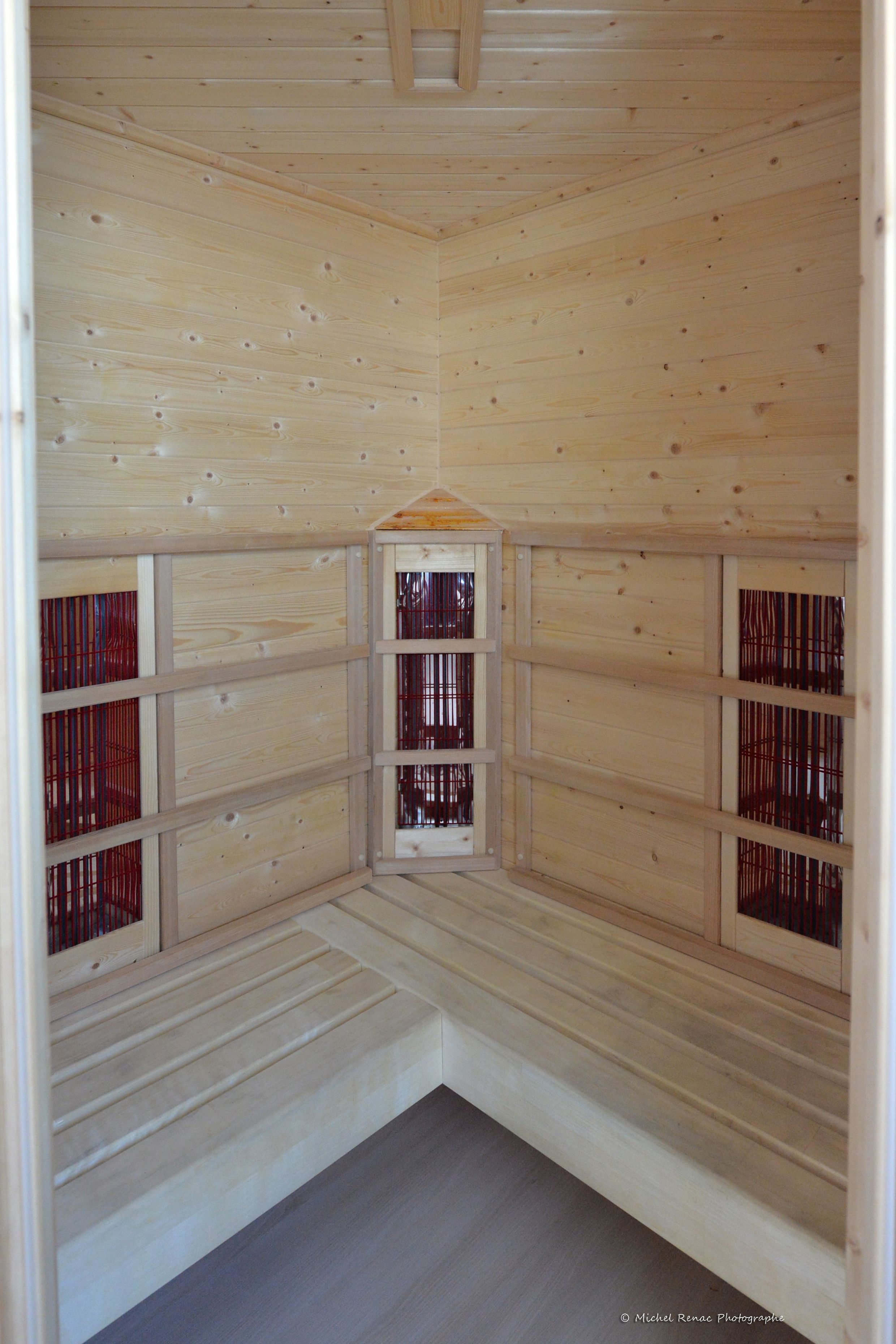 Una habitación de madera con techo inclinado, paredes de madera y una ventana central.