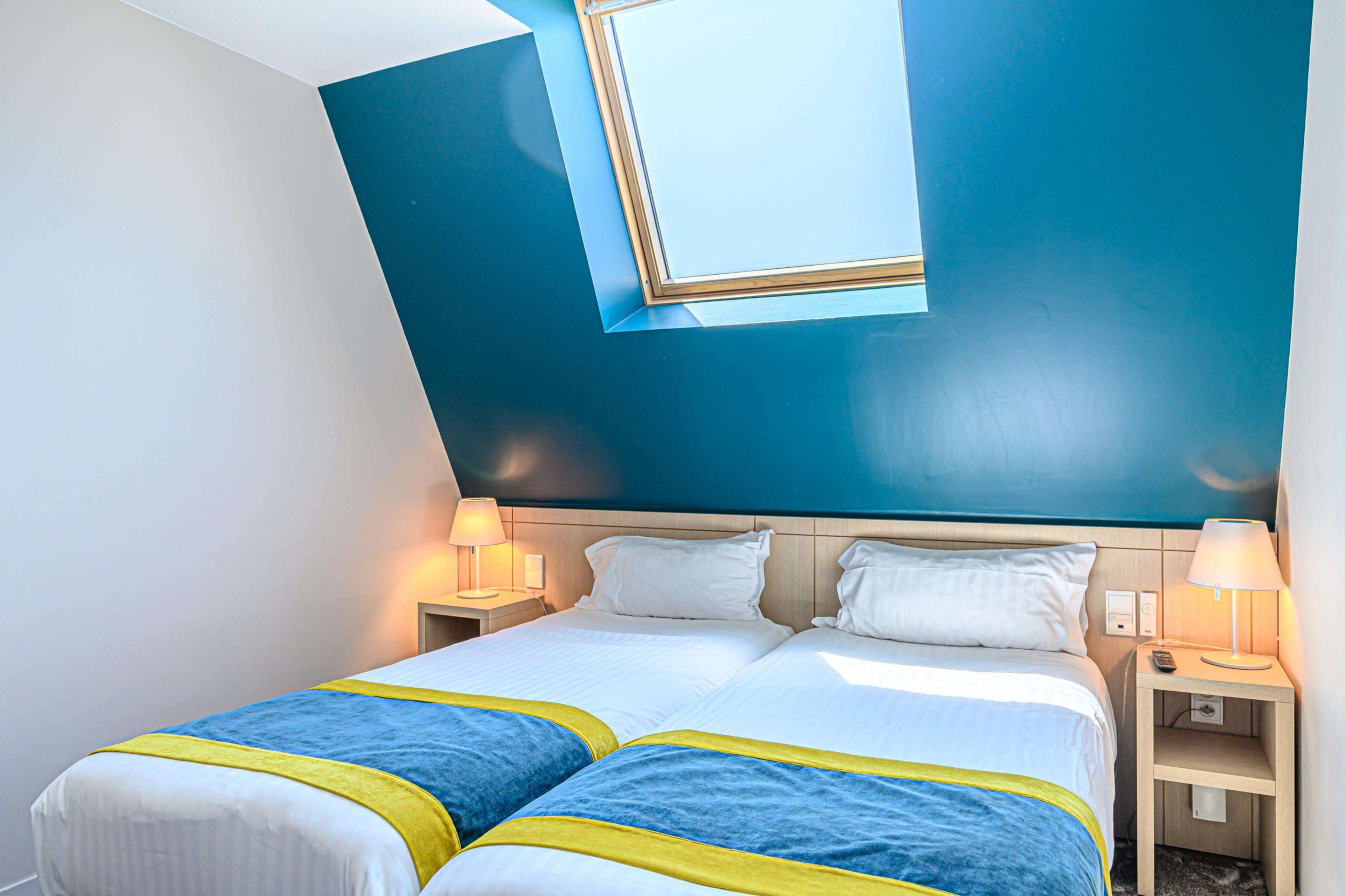 Een hotelkamer met twee bedden, een groot raam en bedlampen.