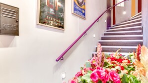 Una escalera con barandilla morada, un buzón para llaves fijado a la pared y un cartel del Festival du Film 2005.