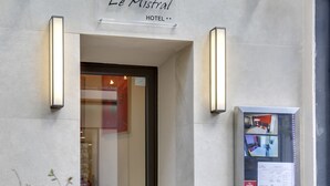 La entrada al Hotel Le Mistral, con un cartel sobre la puerta y una cámara de seguridad en la pared.
