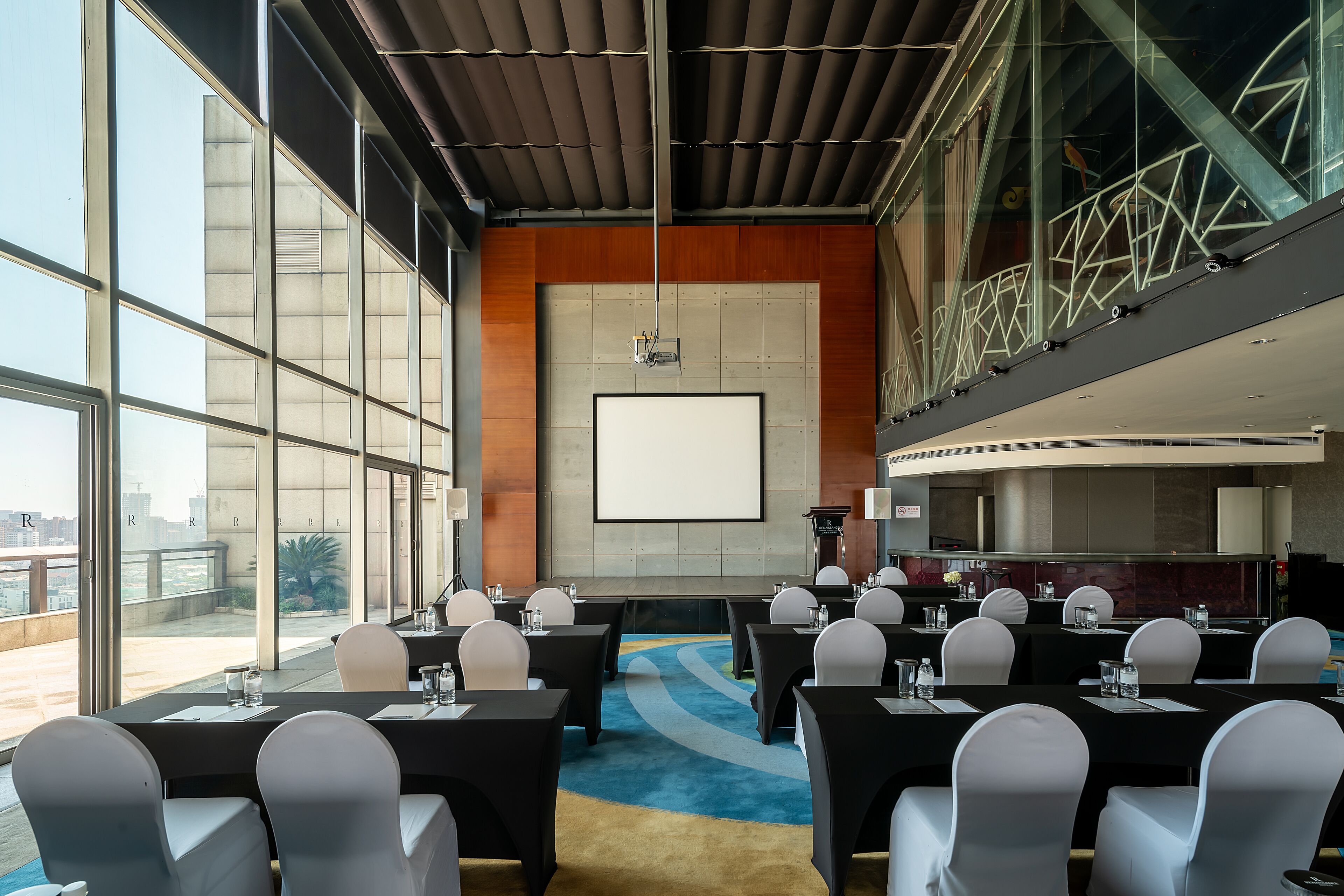 Een vergaderzaal met een groot scherm, meerdere tafels en stoelen, klaar voor vergaderingen.