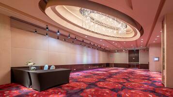 A conference room with a large table, a chandelier, and a patterned carpet.