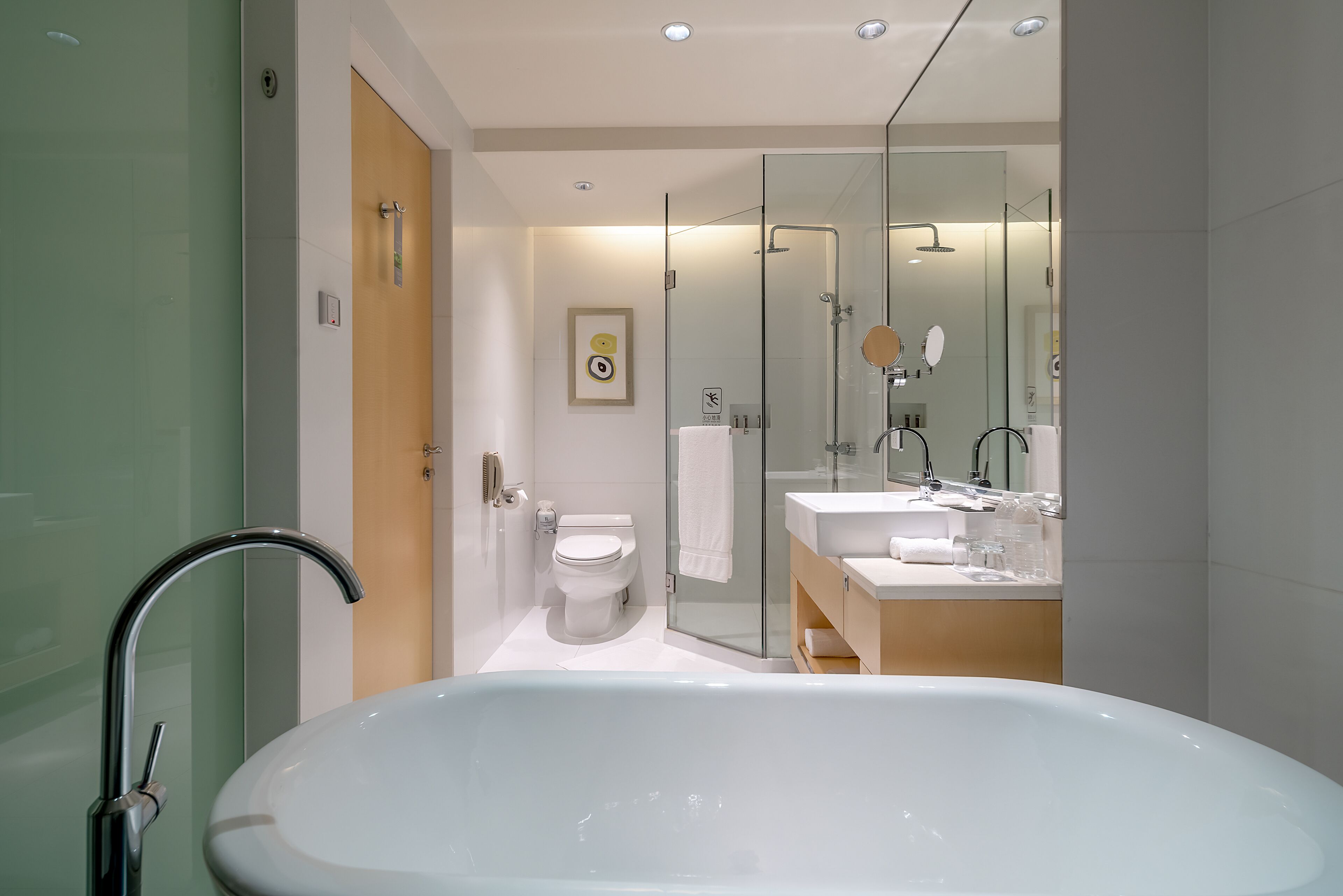 A modern bathroom with a large bathtub, a glass shower enclosure, and a wooden vanity with a mirror.