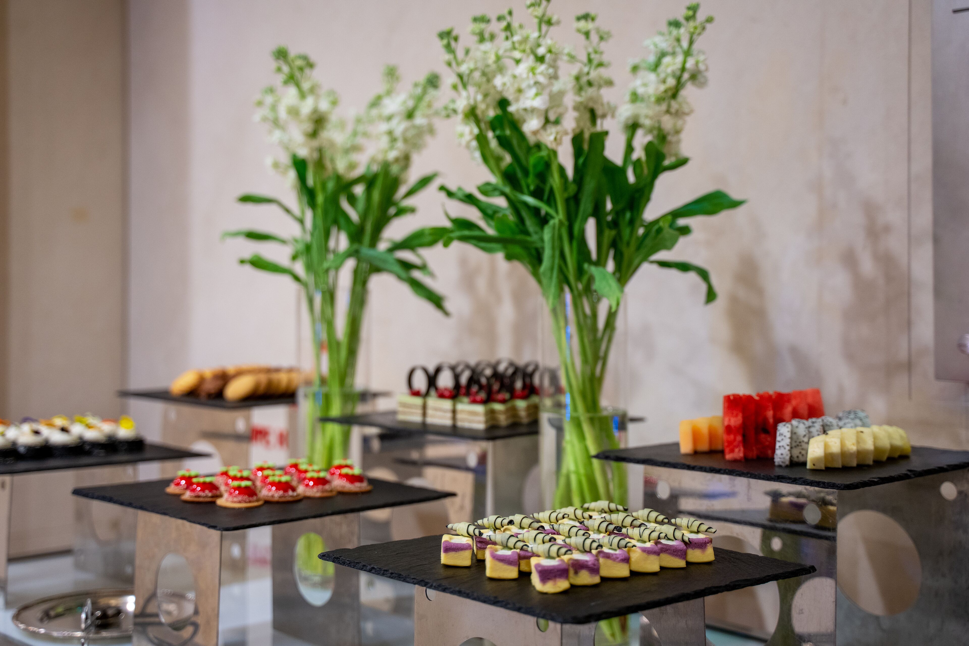 A buffet table with various food items and a vase of flowers.