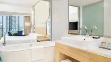 A modern hotel bathroom with a large bathtub, a double sink, and a large mirror.