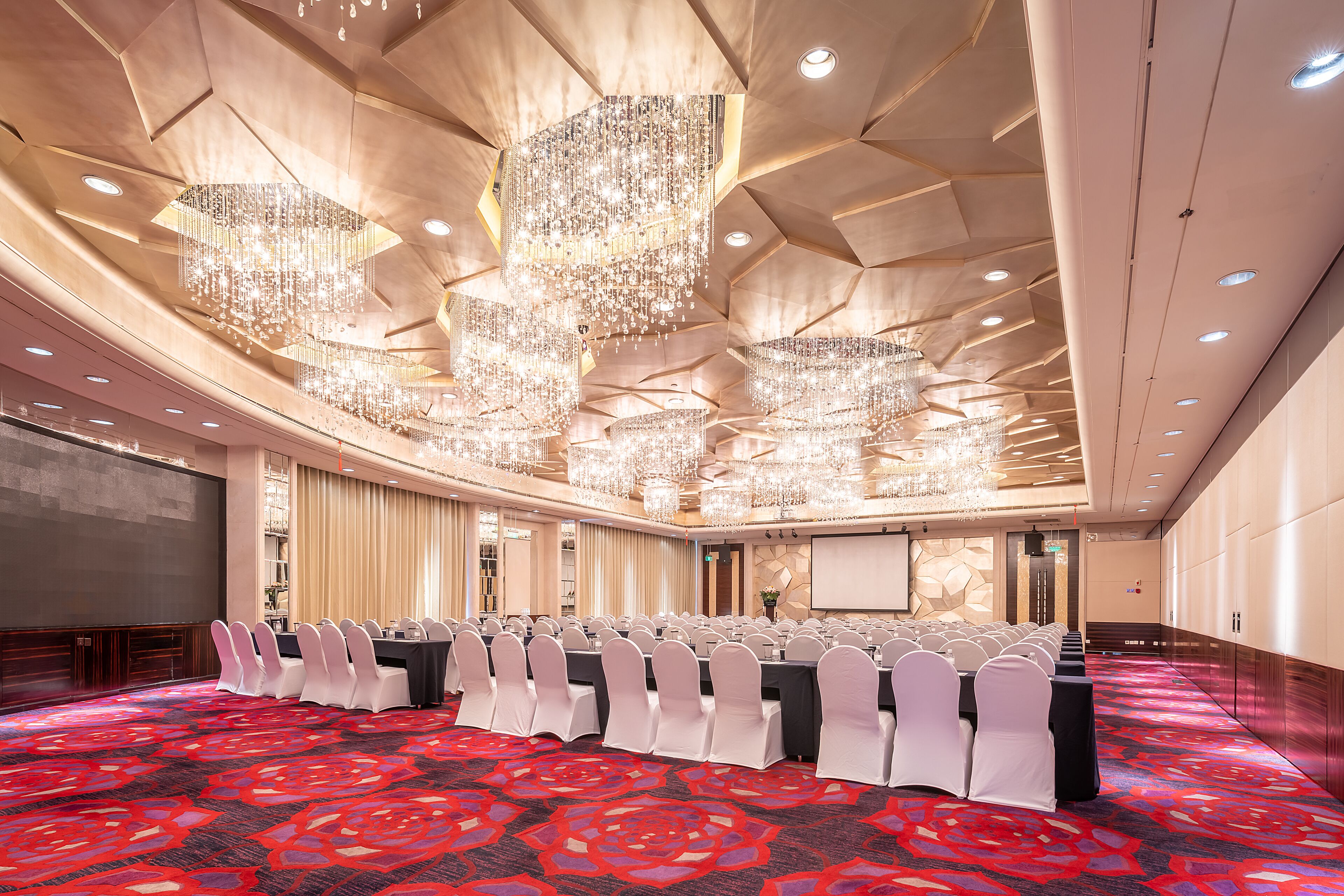 A conference room with a long table, white chairs, and a red carpet.
