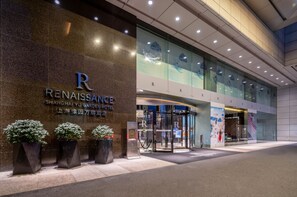 The exterior of the Renaissance Shanghai Yu Garden Hotel with a prominent entrance, glass doors, and potted plants.
