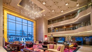 A spacious lobby with a large chandelier, comfortable seating, and a view of the cityscape through expansive windows. - Renaissance Shanghai Yu Garden Hotel on the Bund by Nanjing Road (Shanghai)