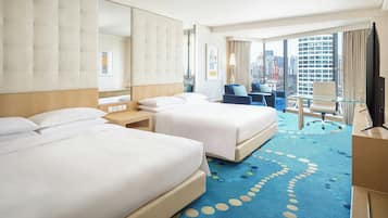 A hotel room with two beds, a large mirror, a desk, a chair, and a TV.