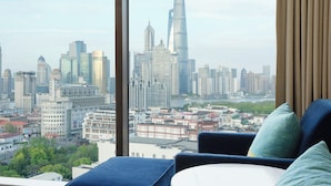 A cityscape view from a hotel room with a large window, featuring modern buildings and a river. - Renaissance Shanghai Yu Garden Hotel on the Bund by Nanjing Road (Shanghai)
