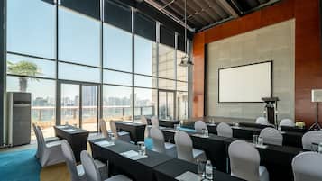 A conference room with large windows, a presentation screen, and a podium.