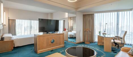 Una habitación de hotel moderna con una cama grande, televisión, una mesa de centro redonda, un sofá y un escritorio con silla.