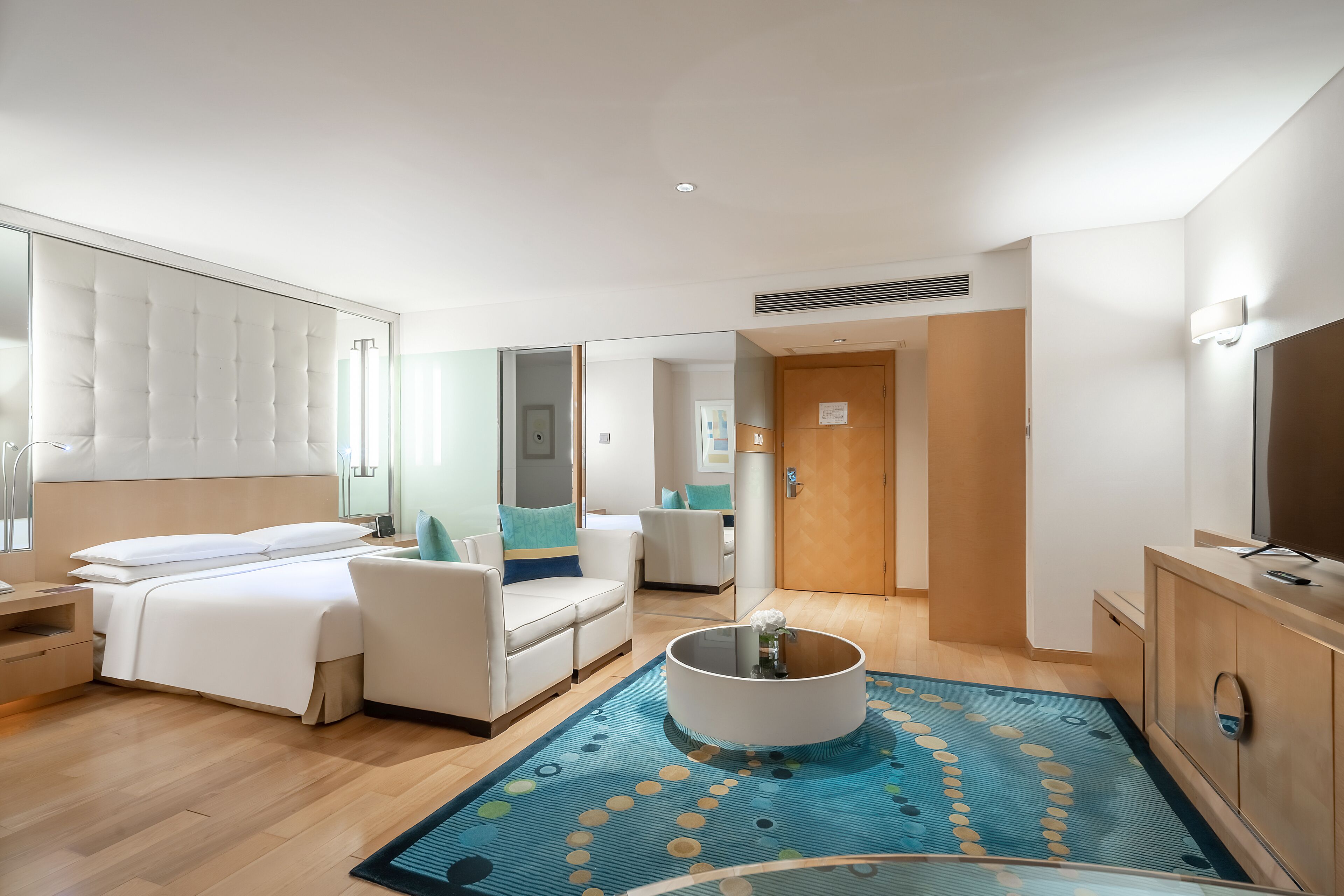Habitación de hotel con cama, sofá, mesa de centro y televisión.