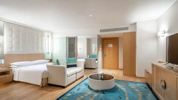 A hotel room with a bed, a sofa, a coffee table, and a TV.