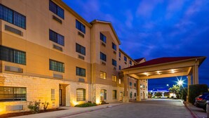 A multi-story hotel with a stone facade, large windows, and a covered entrance area. - Best Western Windsor Pointe Hotel & Suites-Frost Bank Center (San Antonio)