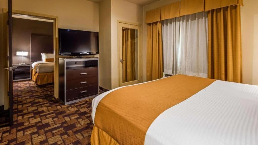 Een hotelkamer met een bed, een televisie, een bureau en een kledingkast.