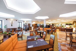 Um hall de hotel com área de estar central, cozinha e balcão de recepção.