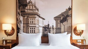 Une chambre d’hôtel avec un grand lit, deux lampes de chevet et une fresque murale représentant un paysage urbain.