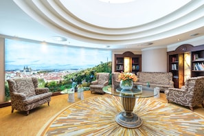 A spacious living room with a glass coffee table, patterned armchairs, and a view of a cityscape. - Lindner Hotel Prague Castle, part of JdV by Hyatt (Prague)
