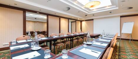 Un salón de conferencias con mesas largas, sillas y una pizarra.