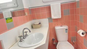 Un baño con lavamanos, inodoro y ventana.