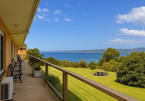 Un balcon avec des meubles d’extérieur, une vue sur la mer et une table de pique-nique.