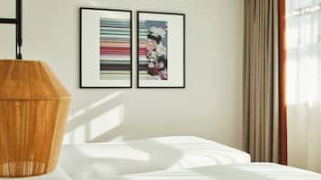 Una habitación de hotel con una cama, una lámpara de madera y dos cuadros en la pared.