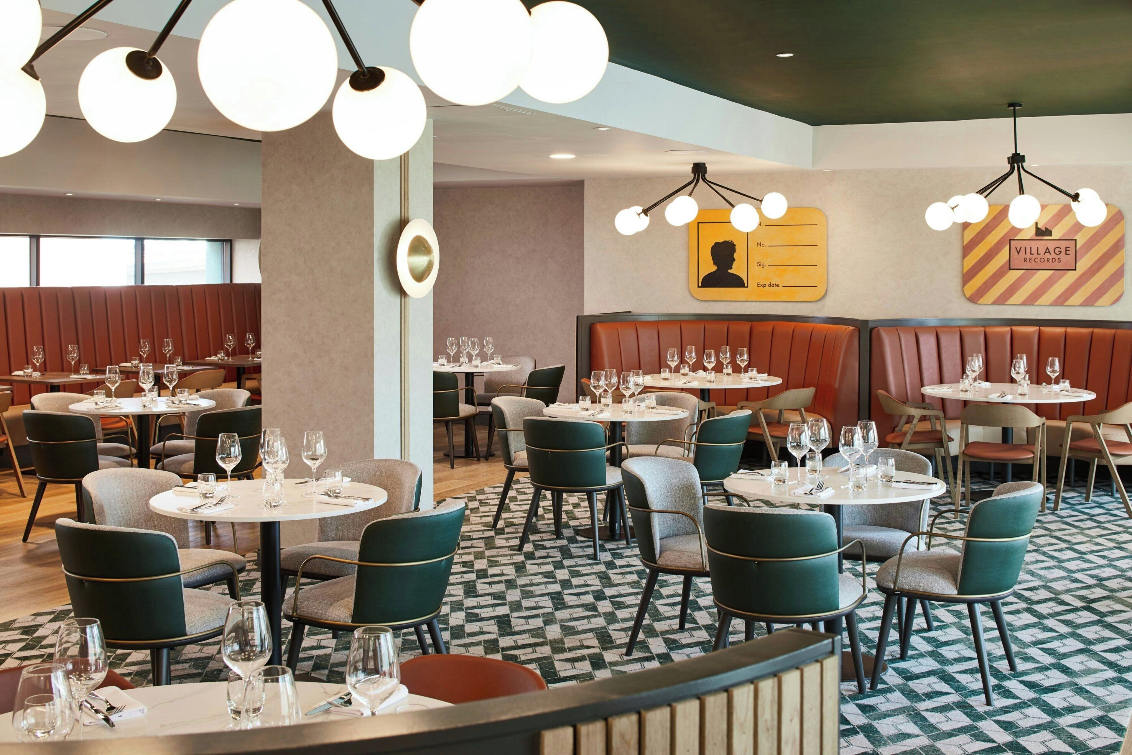 Un restaurant avec des tables rondes, des chaises vertes et un sol à motifs.