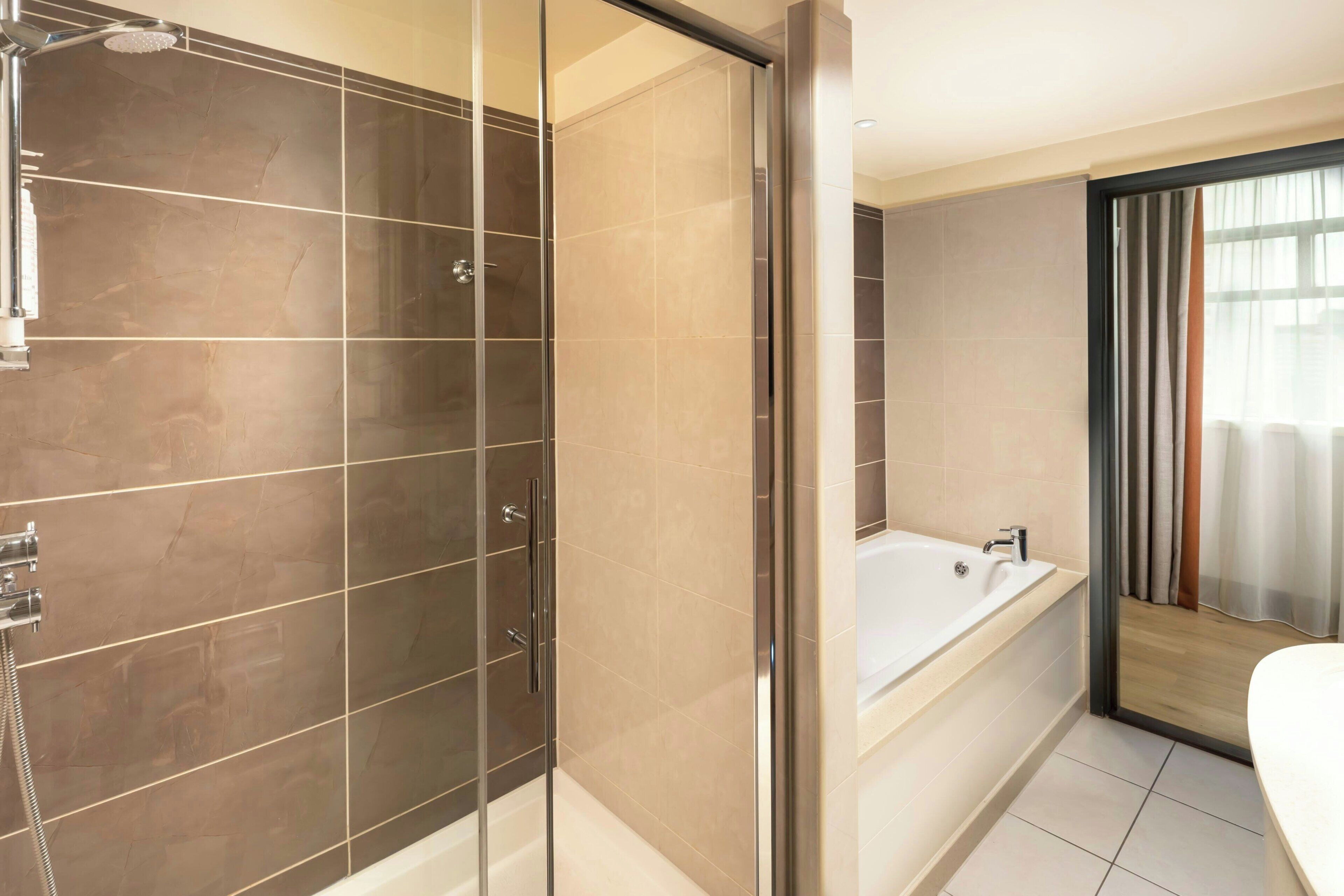 A modern bathroom with a glass-enclosed shower, a bathtub, and a toilet.