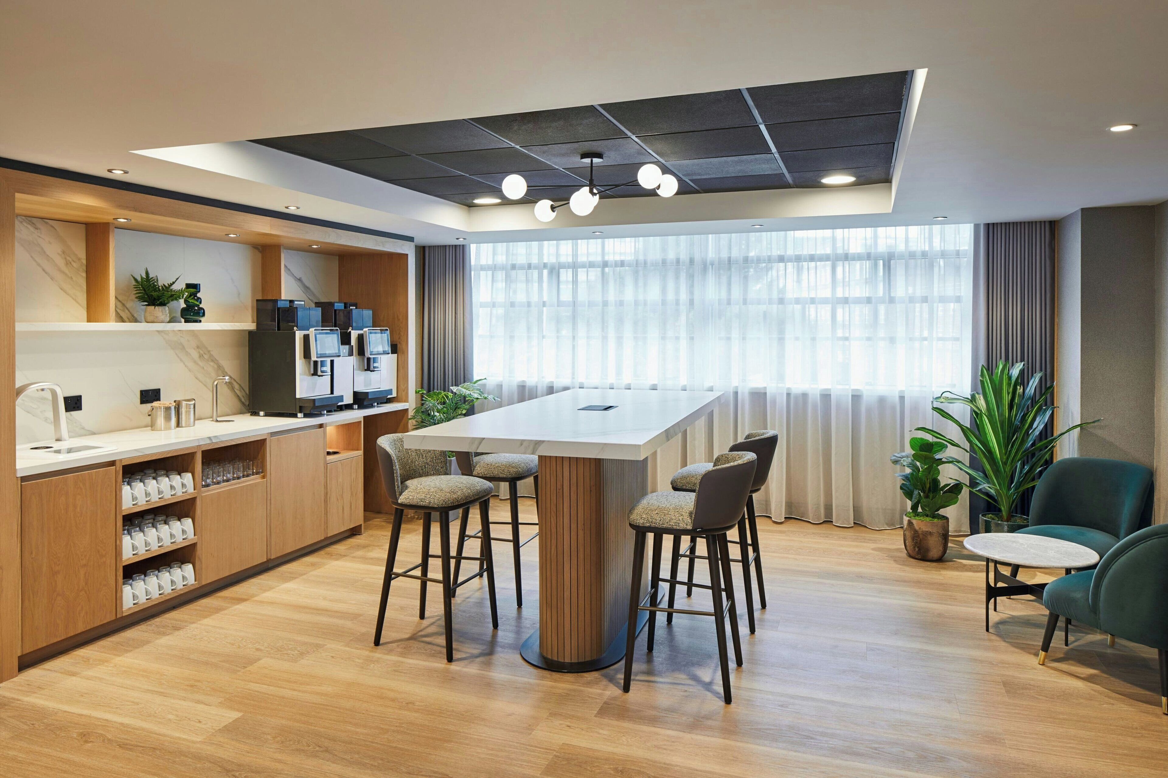 A modern kitchen with a central island, bar stools, and a seating area with a table and chairs.