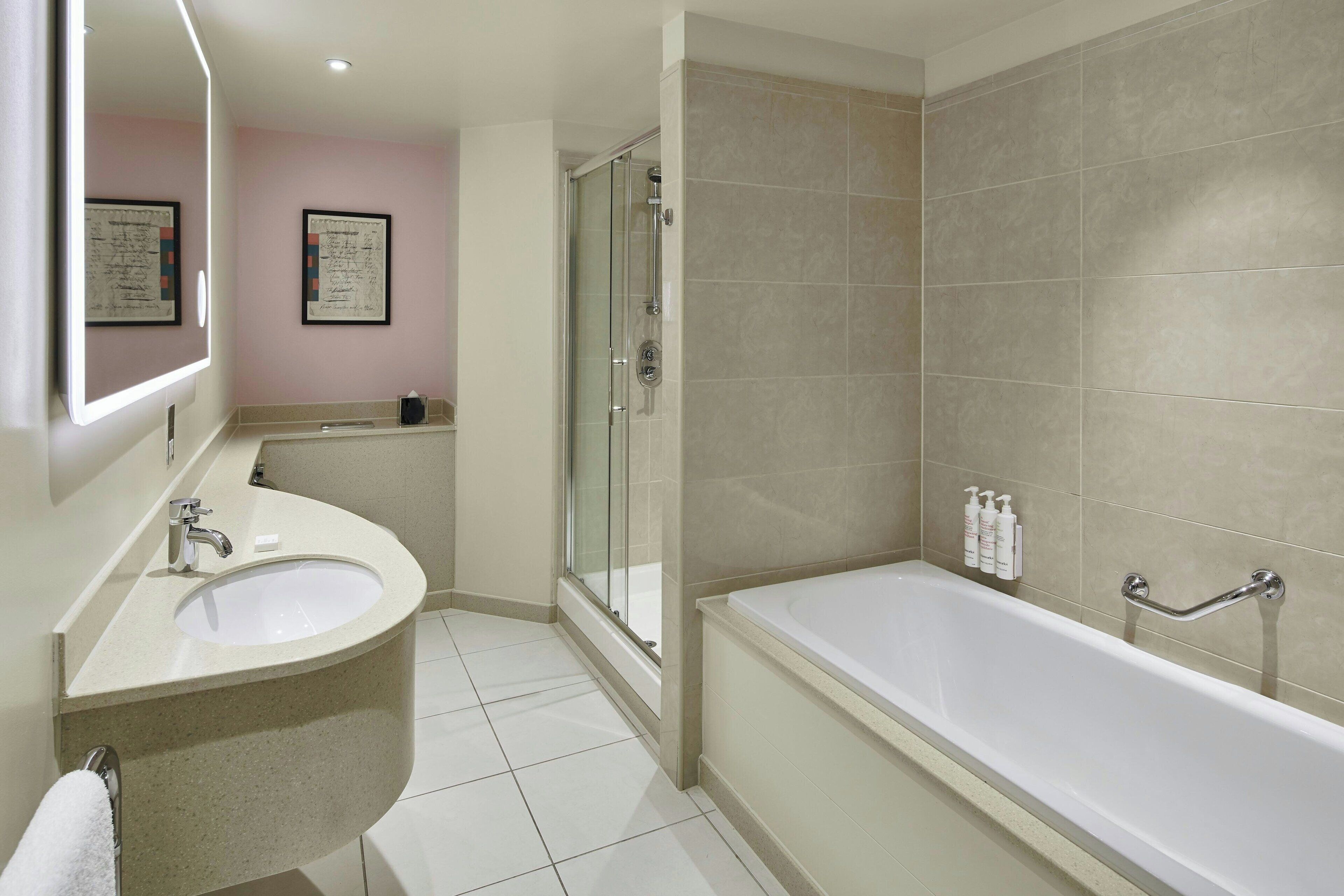 Ein modernes Badezimmer mit Waschbecken, Spiegel, Dusche und Badewanne.