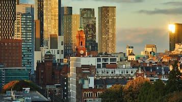 A cityscape with modern high-rise buildings, a train on an elevated track, and a mix of older and newer architecture.