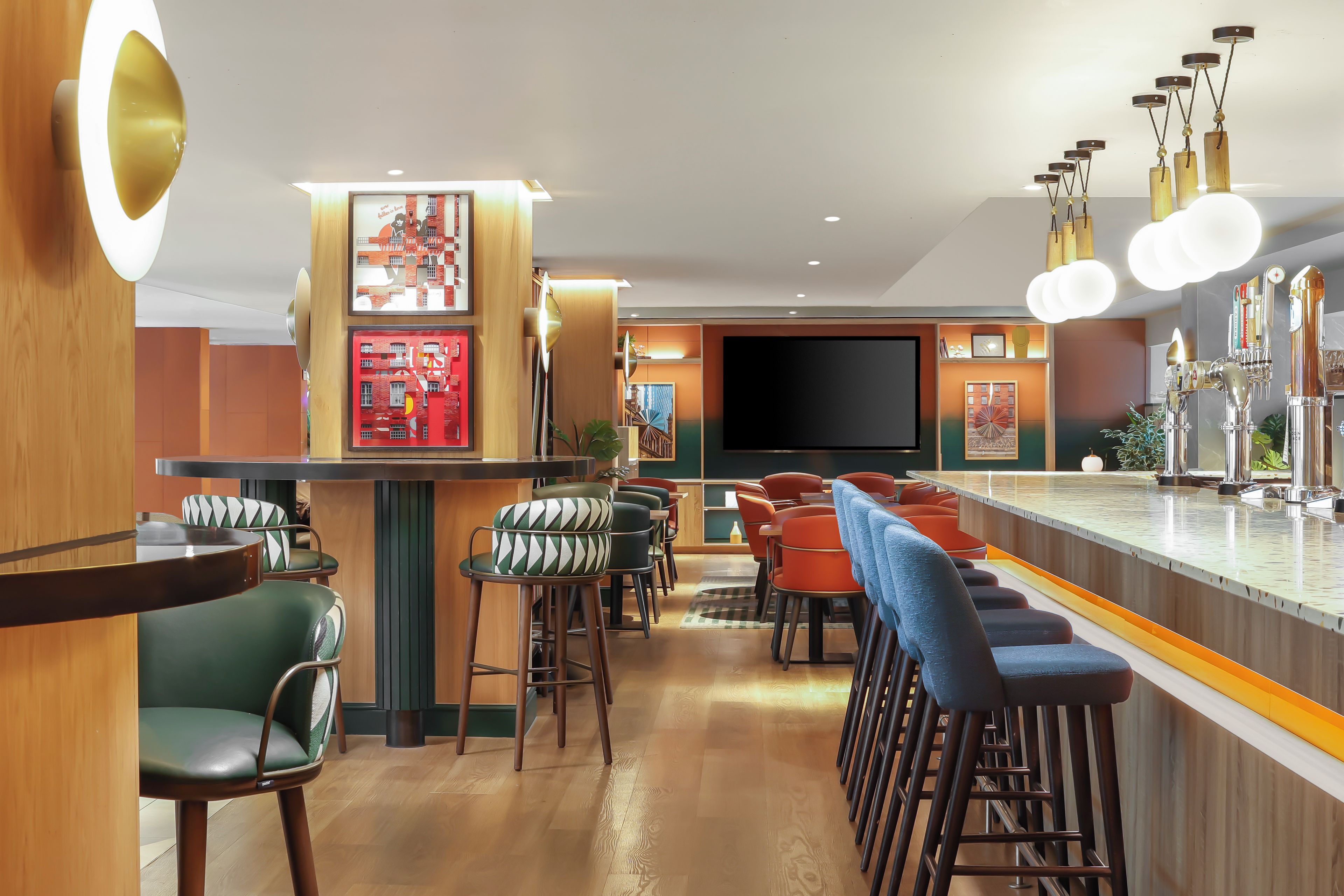 A bar area with stools, a counter, and a television screen.