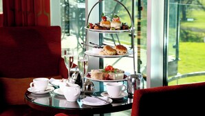 A three-tiered dessert stand with various pastries and a tea service on a table.