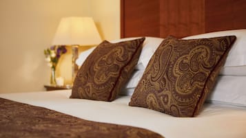 Una cama bien hecha con almohadas estampadas y un cabecero de madera.