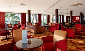 Een hotel lobby met rode bekleding, een receptiebalie en grote ramen.