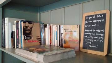 A bookshelf with various books, including 'Friction' by Philippe Djian, and a chalkboard with a message in French.