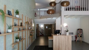 En modern interiör med en receptionsdisk i trä, en trappa och en vägghylla med växter och dekorativa föremål.