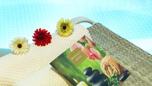 Zona junto a la piscina con una silla de mimbre, un menú y flores decorativas.