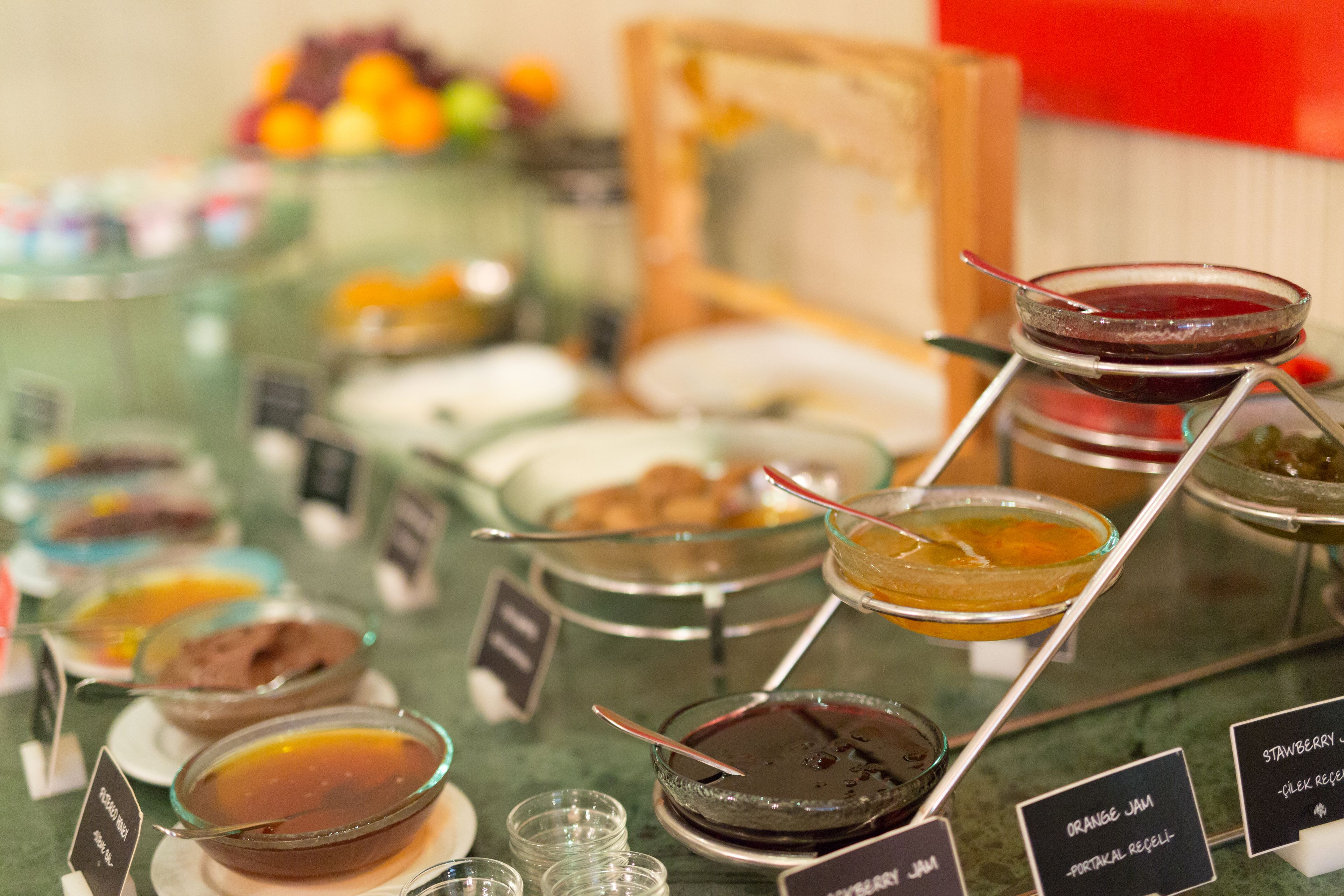 A buffet with various food options including orange jam, chocolate sauce, and other desserts.