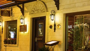 Un edificio con un letrero que dice "Sirkeci Mansion" y una puerta con un panel de vidrio. Hay plantas en macetas y una ventana que ofrece vistas del interior.