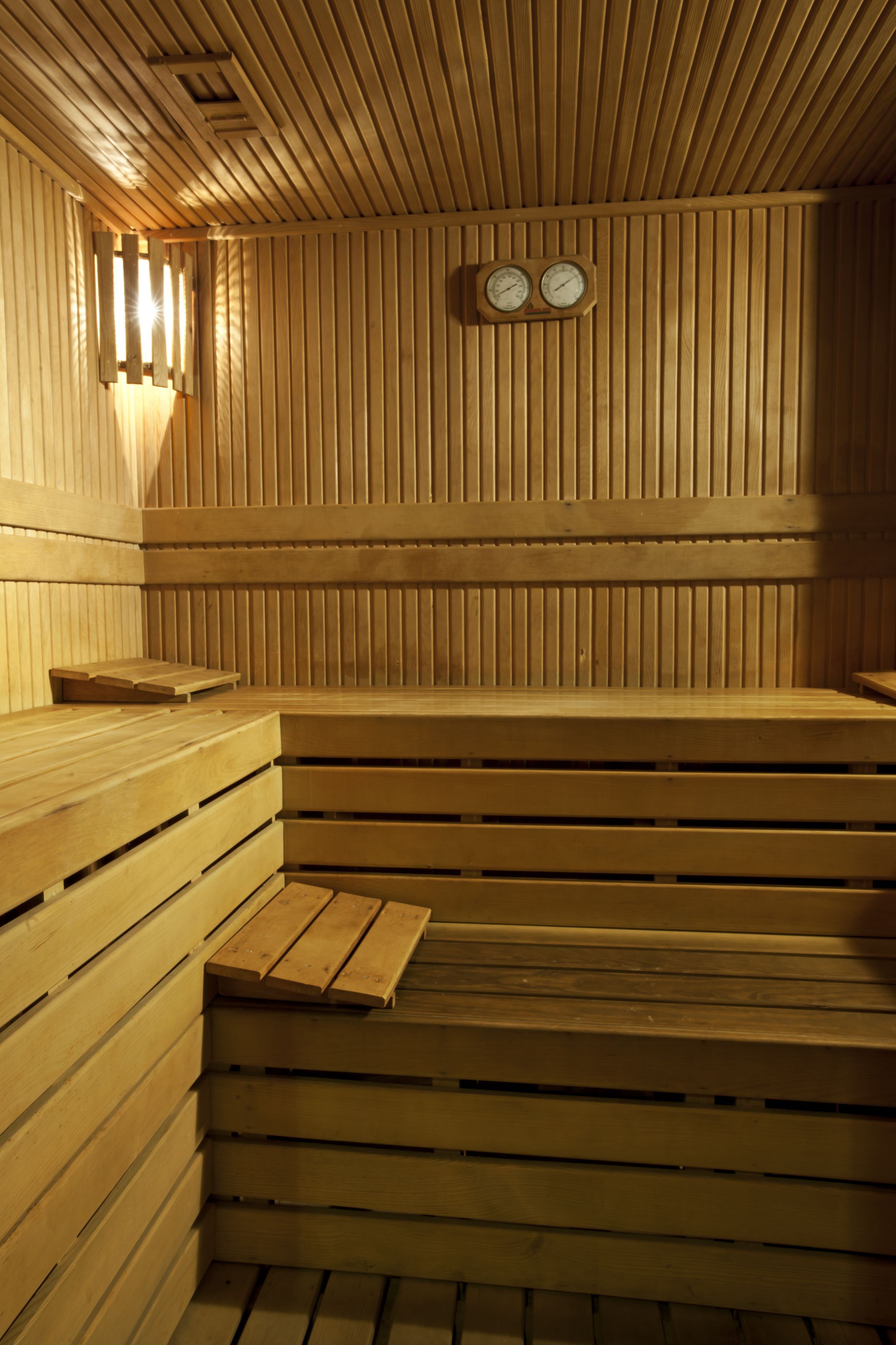 A wooden sauna with benches and a wall-mounted clock.