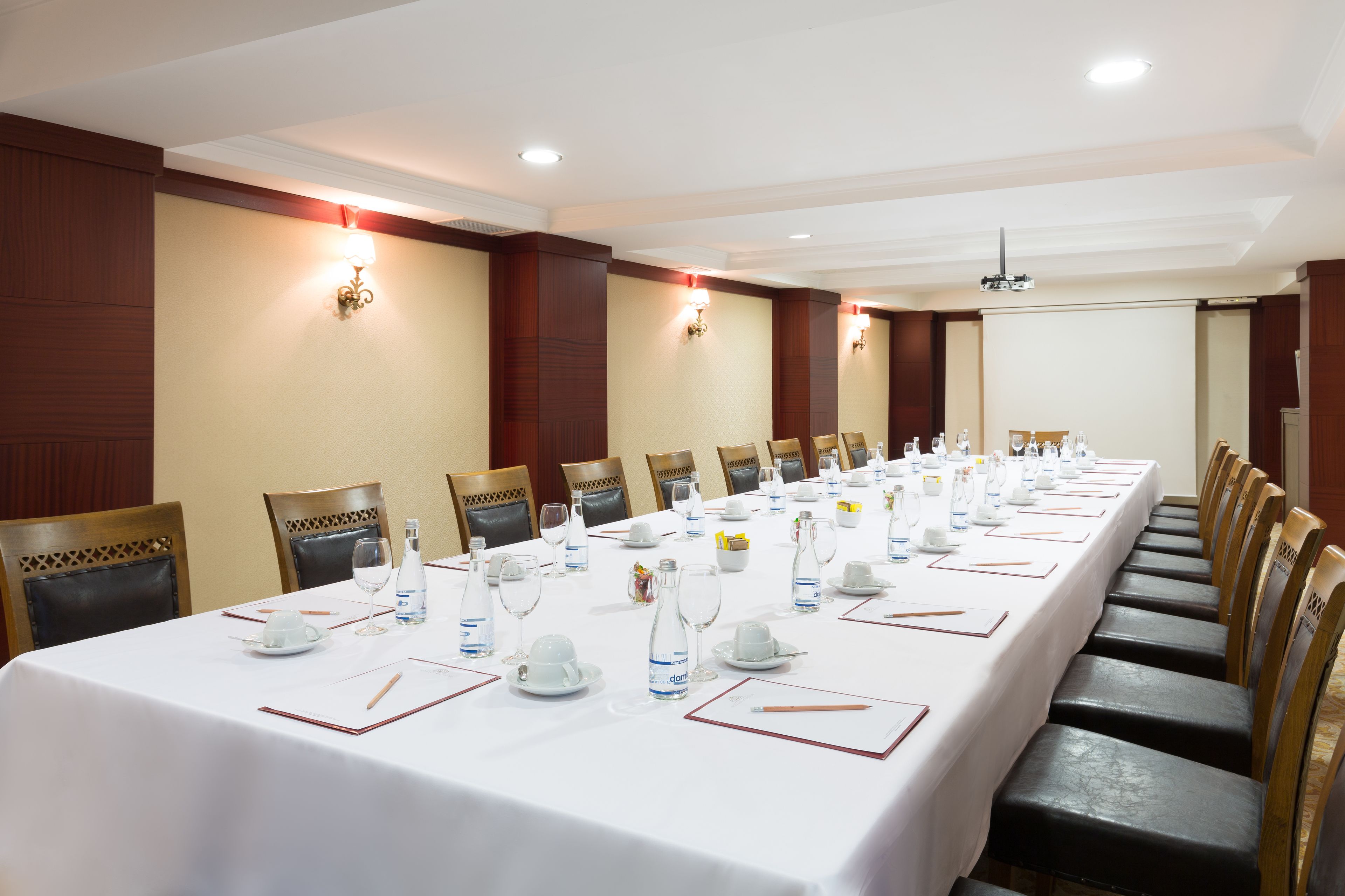 A conference room with a long table set for a meeting, equipped with chairs, water bottles, and glassware.