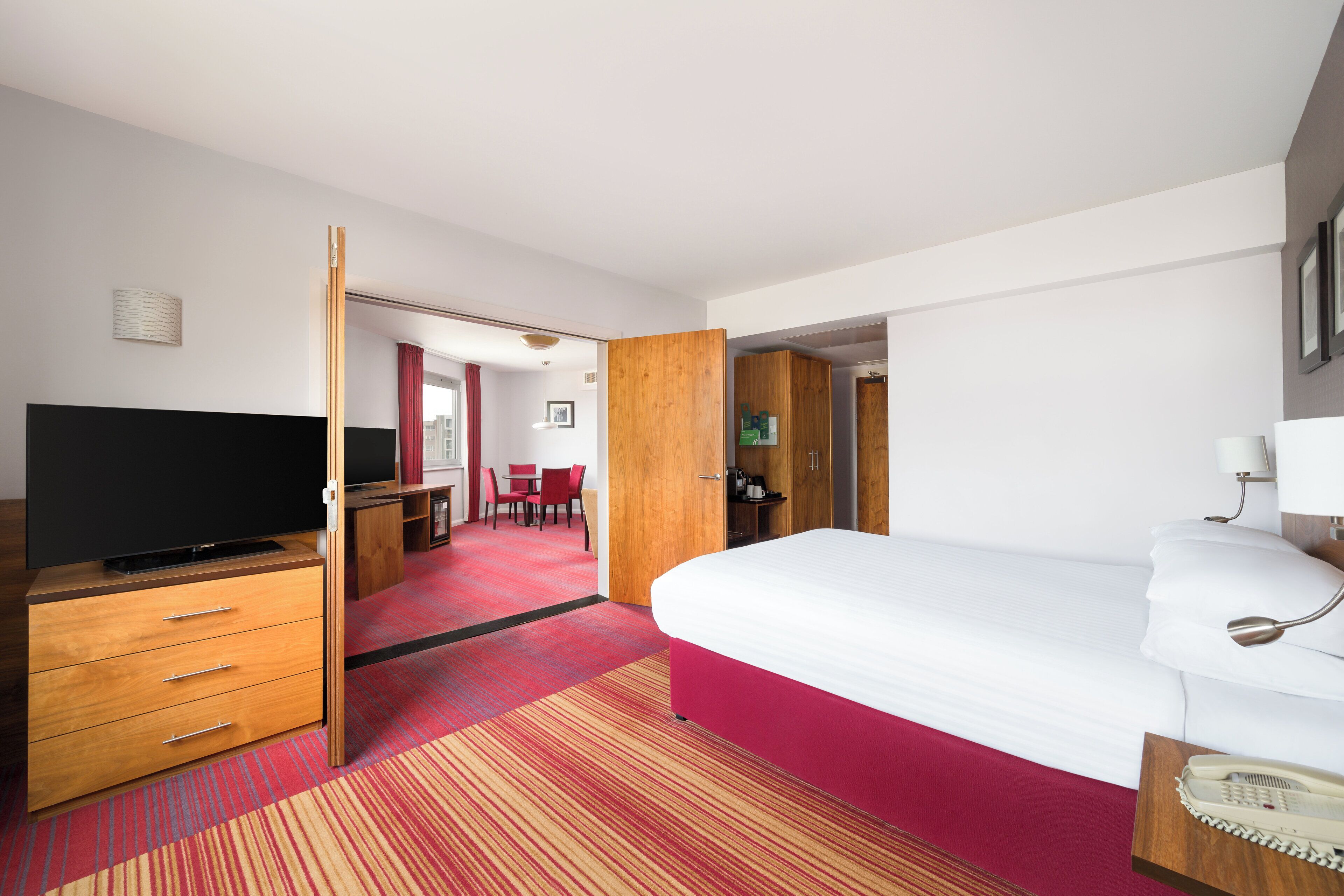 A hotel room with a bed, a TV, a desk, and a chair.