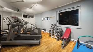 A gym with treadmills, a bench press, and a wall-mounted TV. - Holiday Inn Norwich City by IHG (Norwich)