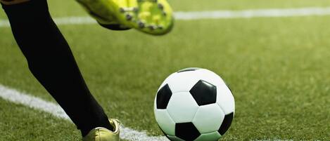 Una pelota de fútbol sobre un campo de césped, con un tapón y un guante en primer plano.