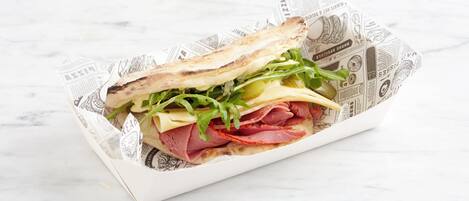 Un sándwich con diferentes ingredientes, sobre una superficie cubierta con papel de periódico.